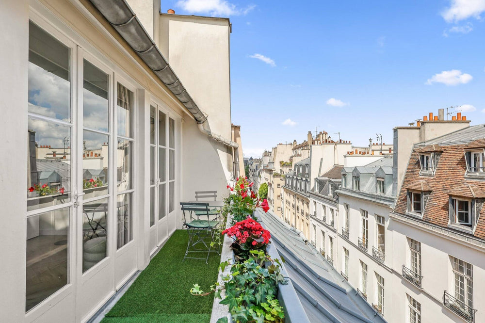 Terrasse fleurie au dernier étage d'un immeuble de l'île Saint-Louis, avec vue sur les toits de Paris