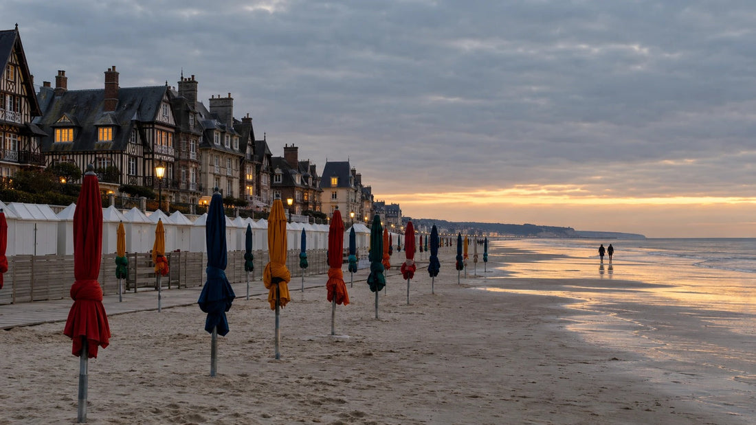 Parasols repliés et cabines fermées sur la plage de Deauville à la tombée du jour en hiver, villas anglo-normandes éclairées en arrière-plan